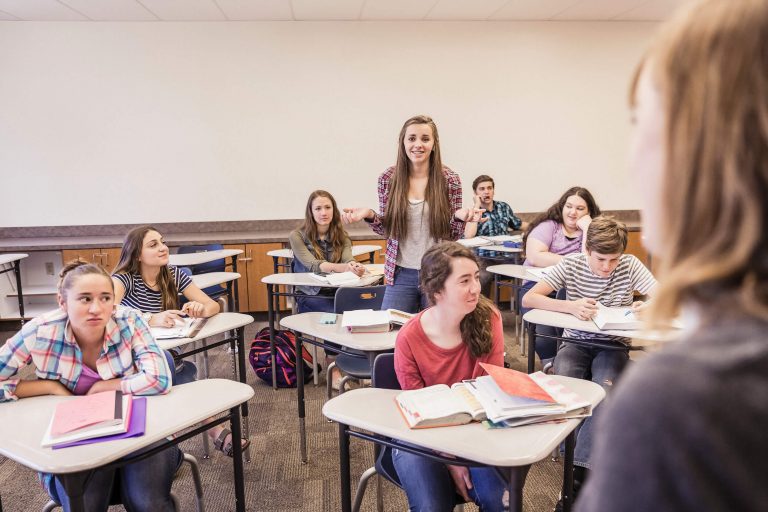 Une élève prenant la parole debout en classe au milieu de ses camarades