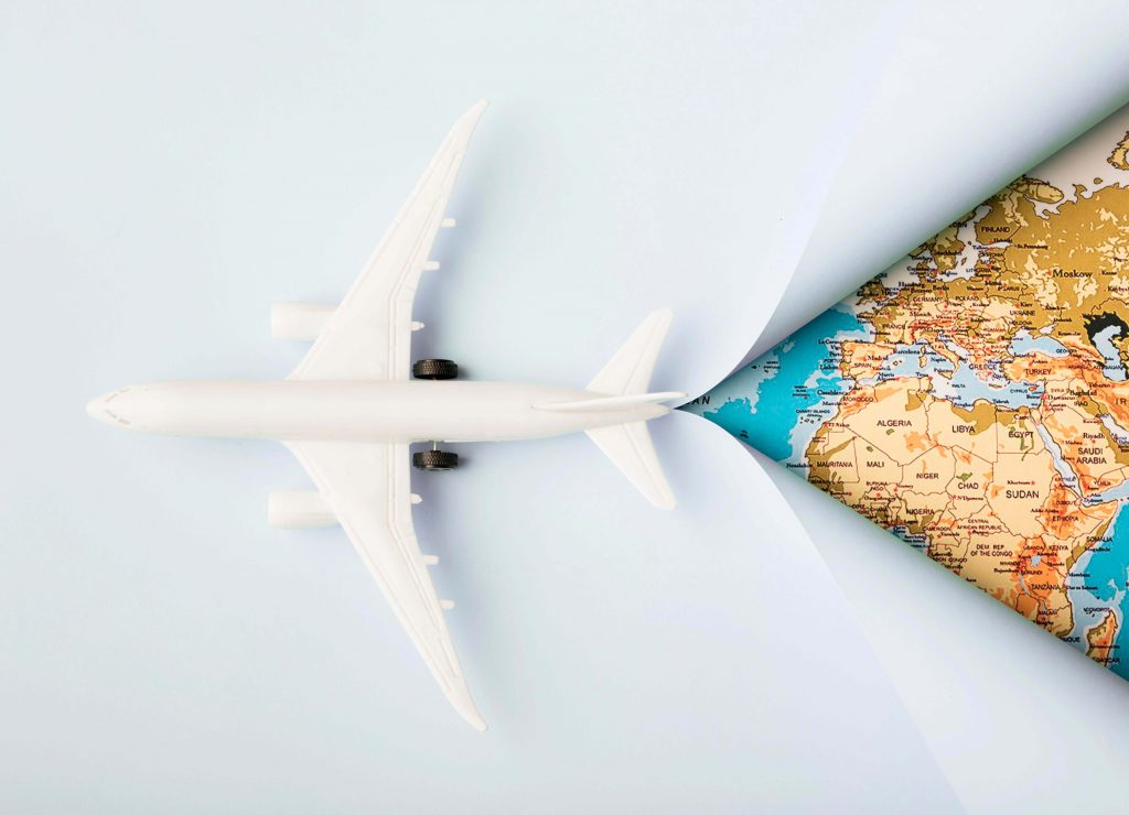 Un avion découpant une feuille de papier avec une carte du monde
