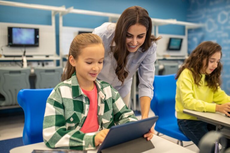 Une professeure aidant une élève travaillant sur un exercice interactif sur tablette